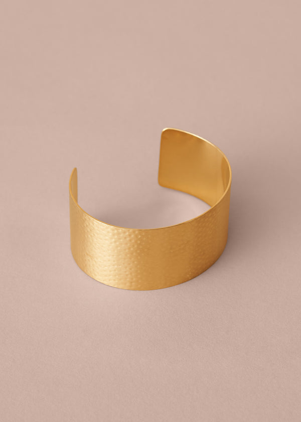 Gold bracelet on a beige background