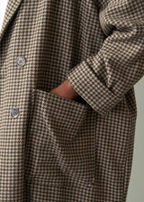 Houndstooth pattern coat with button details on a neutral background