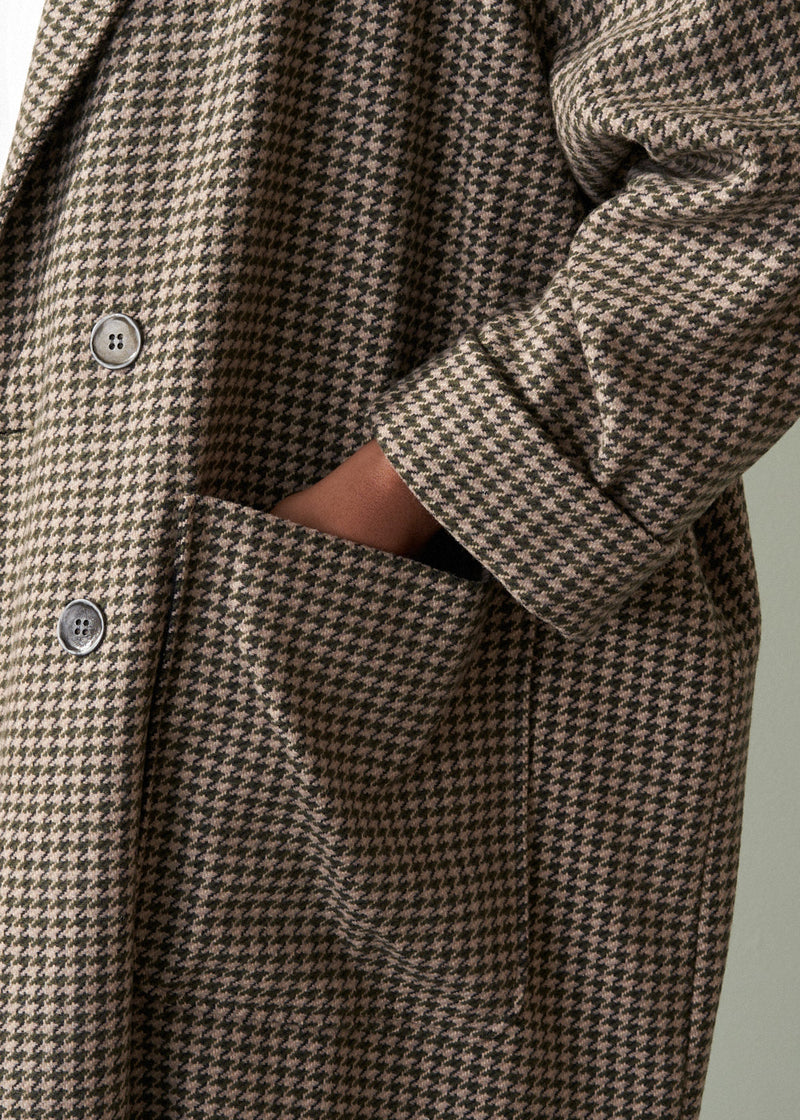 Houndstooth pattern coat with button details on a neutral background