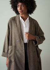 Woman wearing a checkered coat over a white shirt with a neutral background