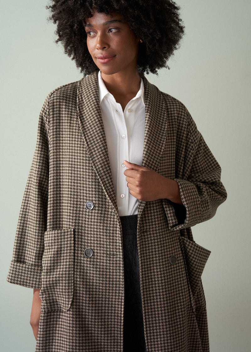 Woman wearing a checkered coat over a white shirt with a neutral background