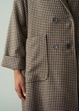 Houndstooth patterned coat with buttons on a plain background
