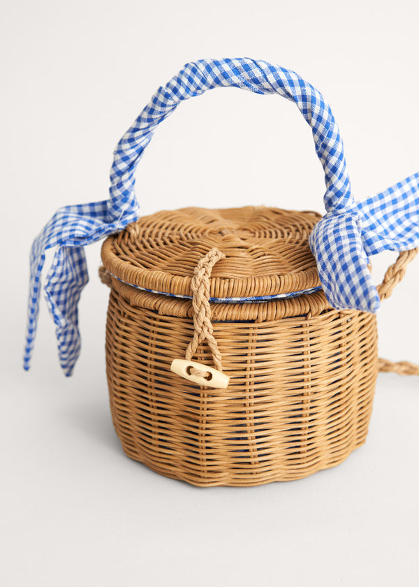 A round wicker basket with a blue gingham handle 