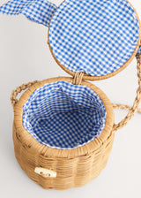 A round wicker basket with a blue gingham handle 