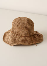 Floppy straw hat with bow detail against a beige background