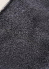 Close-up of a dark charcoal gray textured fabric, showing the fine woven material and a small portion of a light-colored edge in the top-left corner.