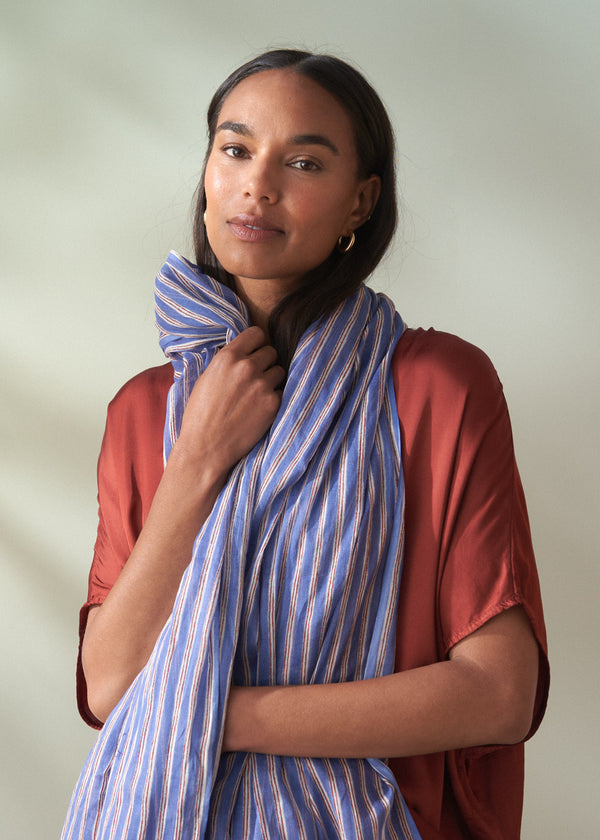 Woman wearing a blue striped scarf against a plain background