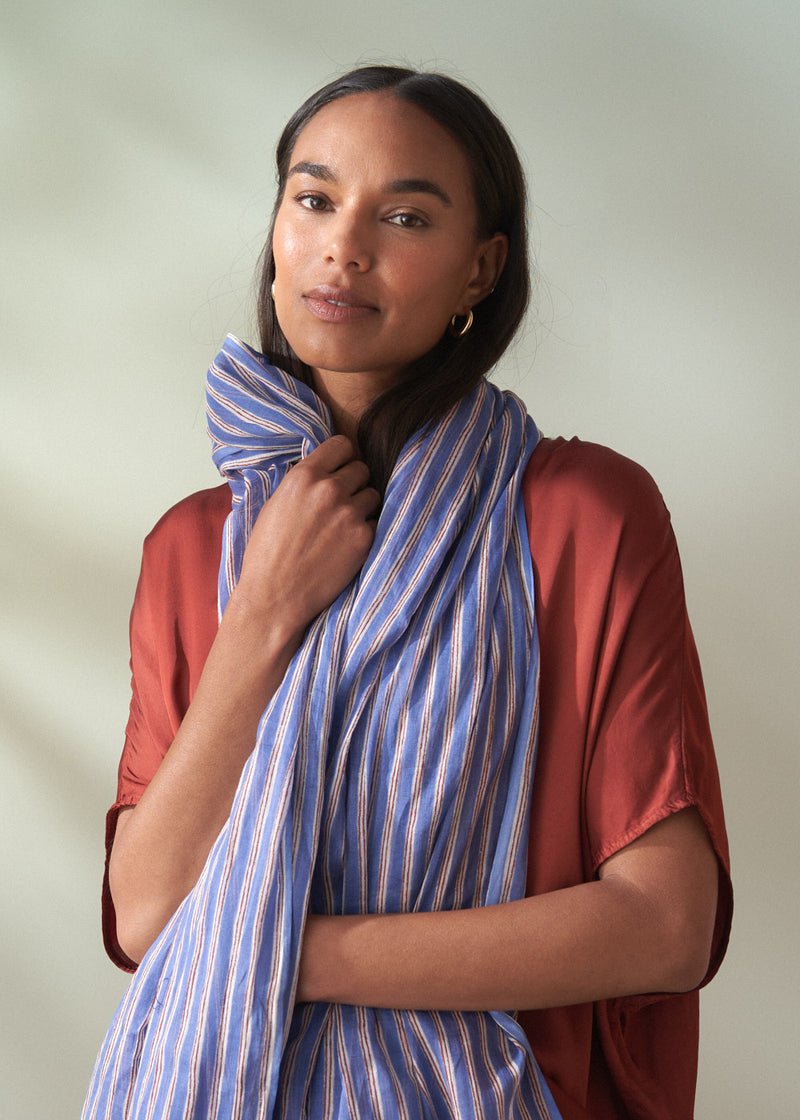 Woman wearing a blue striped scarf against a plain background