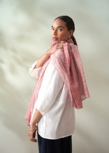 Woman wearing a pink scarf over her shoulder against a plain background