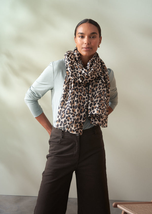 Person wearing a leopard print scarf with a plain background