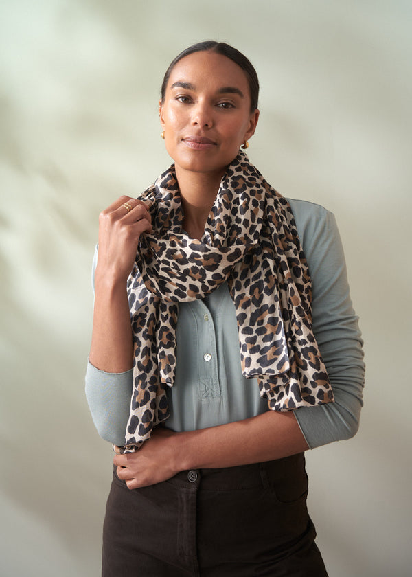 Woman wearing a leopard print scarf against a plain background