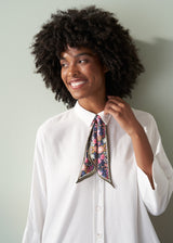 Woman wearing a floral scarf around her neck against a plain background