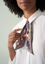 Person wearing a white shirt with a colorful floral tie against a light gray background