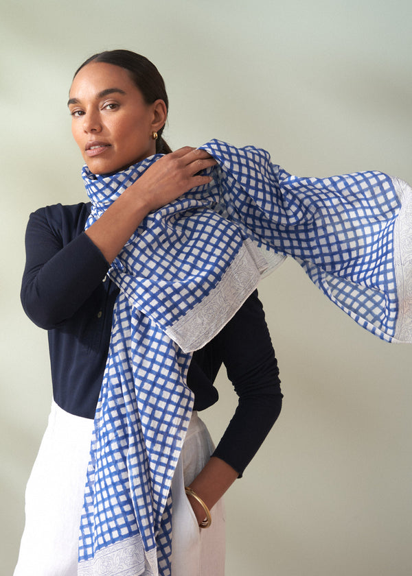 Woman wearing a blue and white checkered scarf against a plain background