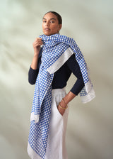 Woman wearing a blue and white checkered scarf against a neutral background
