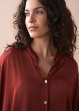 Woman wearing a red blouse against a beige background