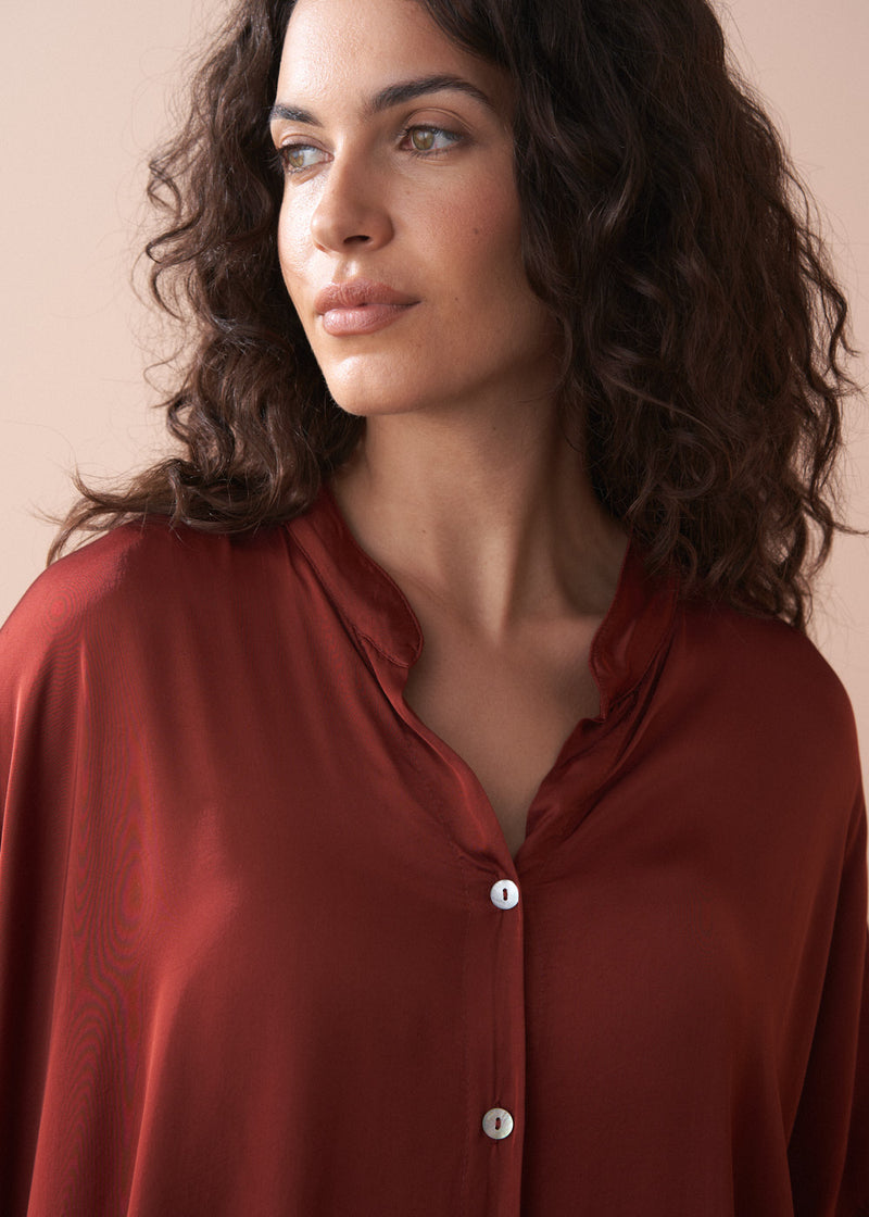 Woman wearing a red blouse against a beige background