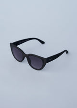 A pair of oversized cat eye sunglasses with black frames and blue lenses