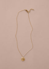 Gold necklace with a pendant on a beige background