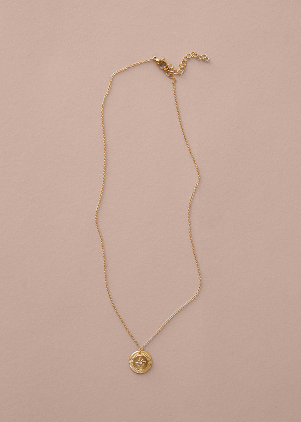 Gold necklace with a pendant on a beige background