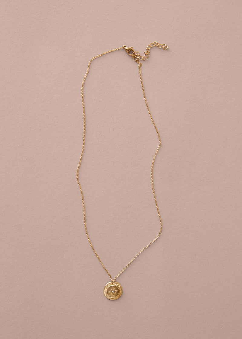 Gold necklace with a pendant on a beige background