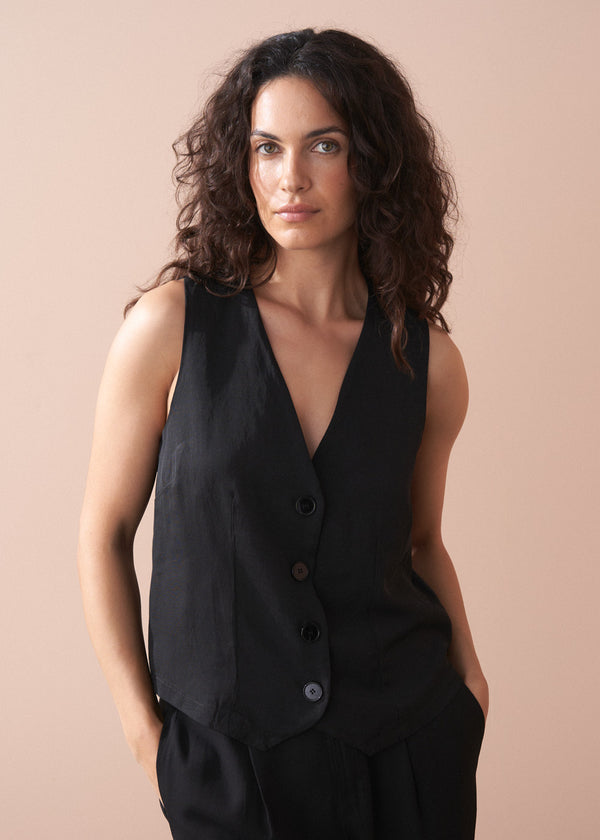 Woman wearing a black button up waistcoat against a beige background
