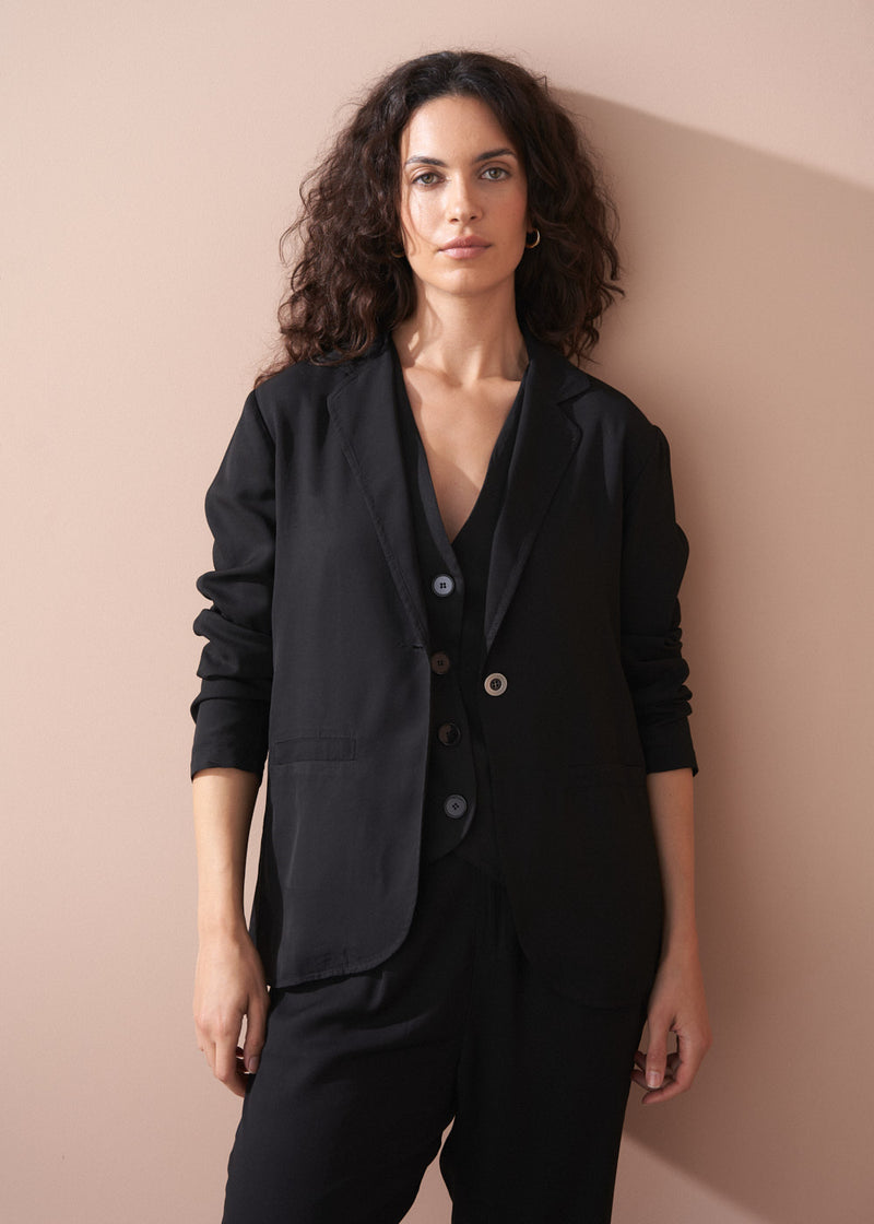 Woman wearing a black outfit against a beige wall
