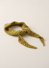A knitted scarf in a textured olive green color, styled in a loose knot on a plain, warm off-white background.