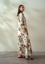 Woman wearing a long, floral dress against a plain background
