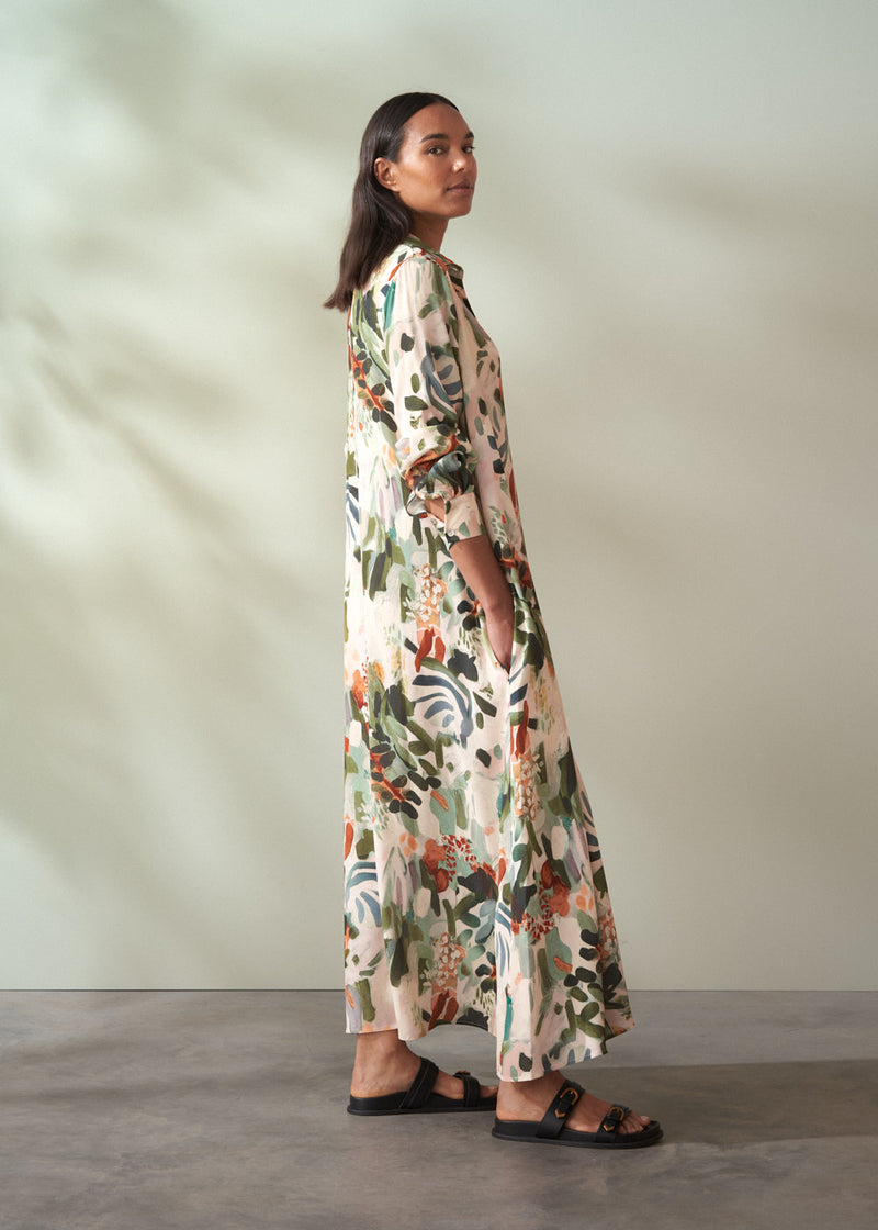 Woman wearing a long, floral dress against a plain background
