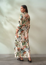 Woman wearing a long, floral-patterned dress against a neutral background