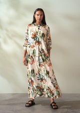 Woman wearing a floral dress standing against a plain background