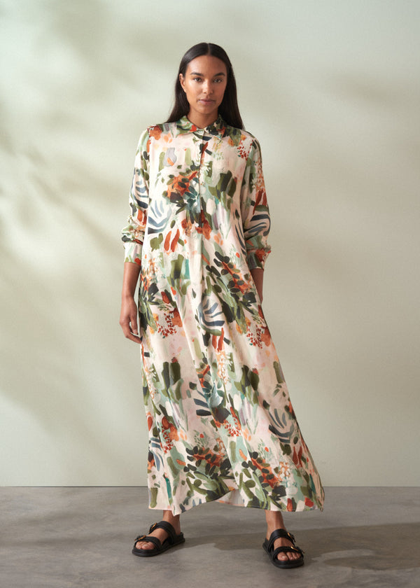 Woman wearing a floral dress standing against a plain background