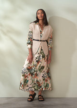 Woman wearing a floral dress with a pink blazer against a neutral background