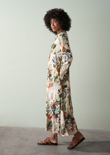 Woman wearing a v-neck floral midi dress with sandals, standing side on against a plain background