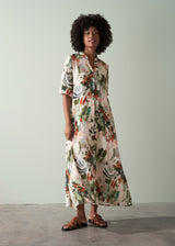 Woman in a v-neck floral midi dress and sandals, standing against a plain background