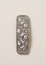 Decorative silver hairclip with gemstones on a beige background