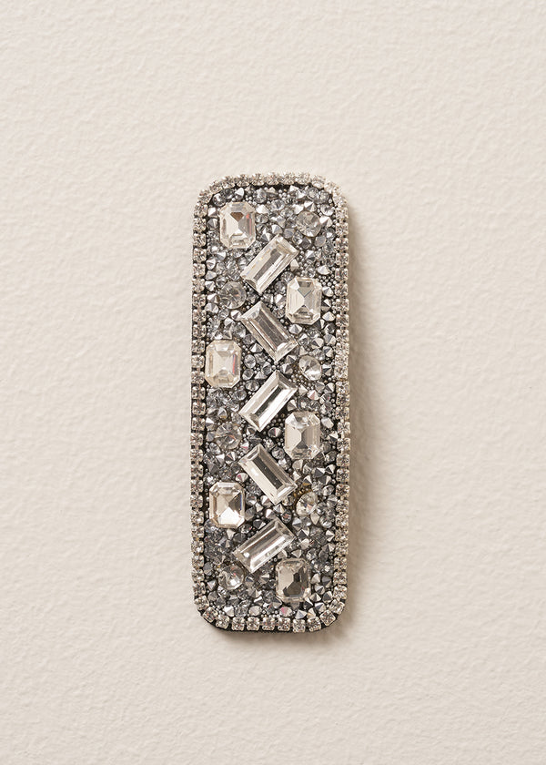 Decorative silver hairclip with gemstones on a beige background