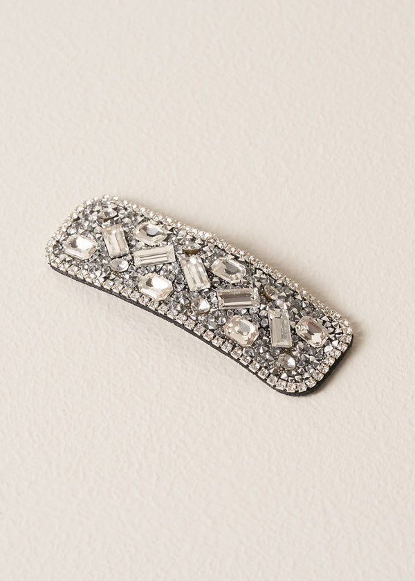 Decorative silver hairclip with gemstones on a beige background