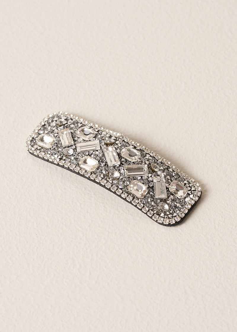 Decorative silver hairclip with gemstones on a beige background