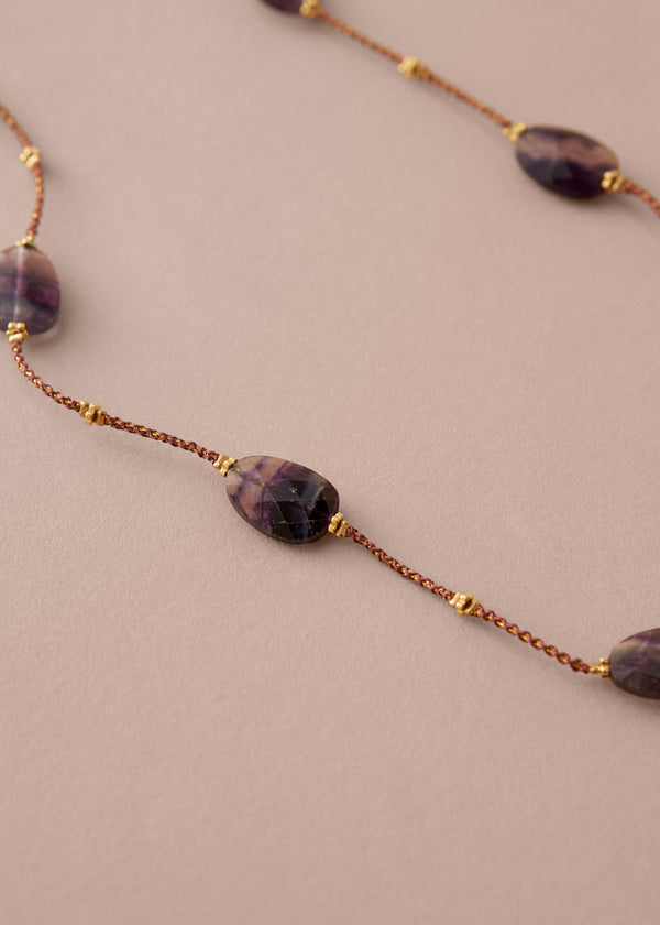 Necklace with purple beads on a beige background