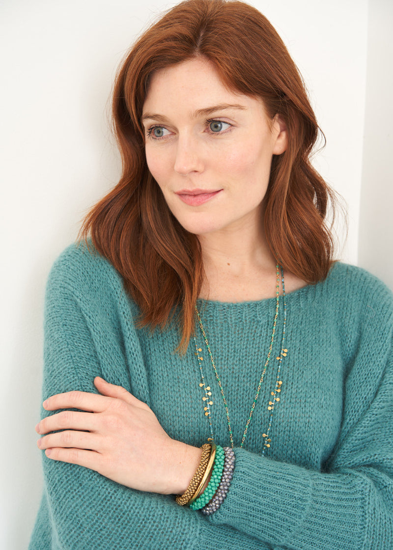 A model wearing a teal green knitted slouchy sweater