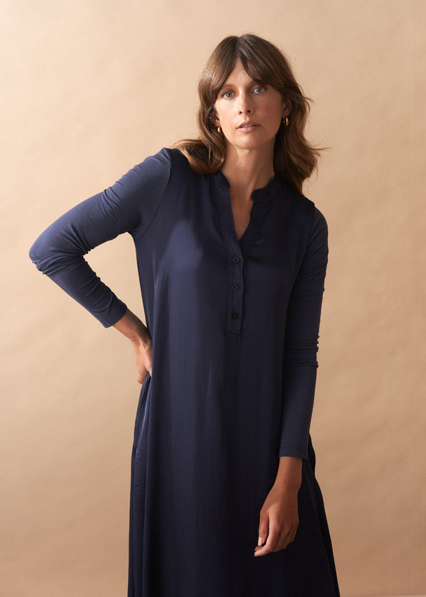 Woman wearing a navy blue dress against a beige background