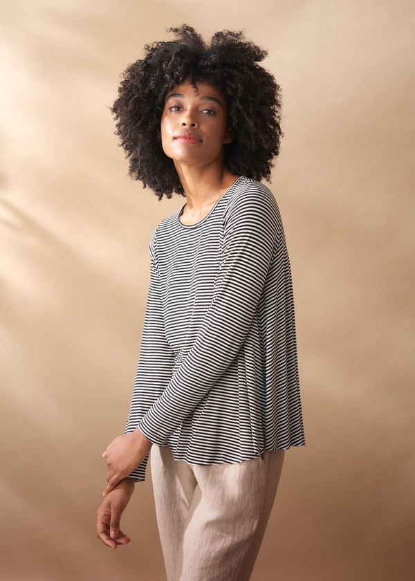 Woman wearing a striped long-sleeve top against a beige background