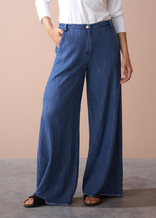 Person wearing blue wide-leg jeans on a neutral background