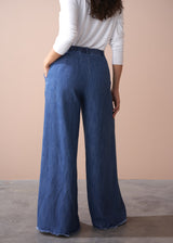 Person wearing blue wide-leg jeans against a beige background