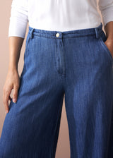 Person wearing blue jeans with a plain background