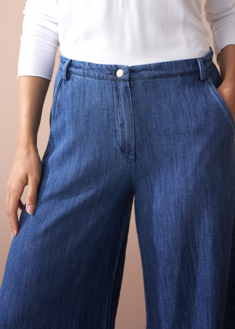 Person wearing blue jeans with a plain background