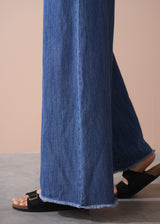 Blue denim pants being worn on a neutral background
