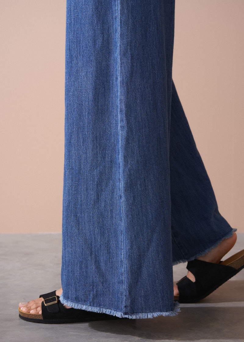 Blue denim pants being worn on a neutral background